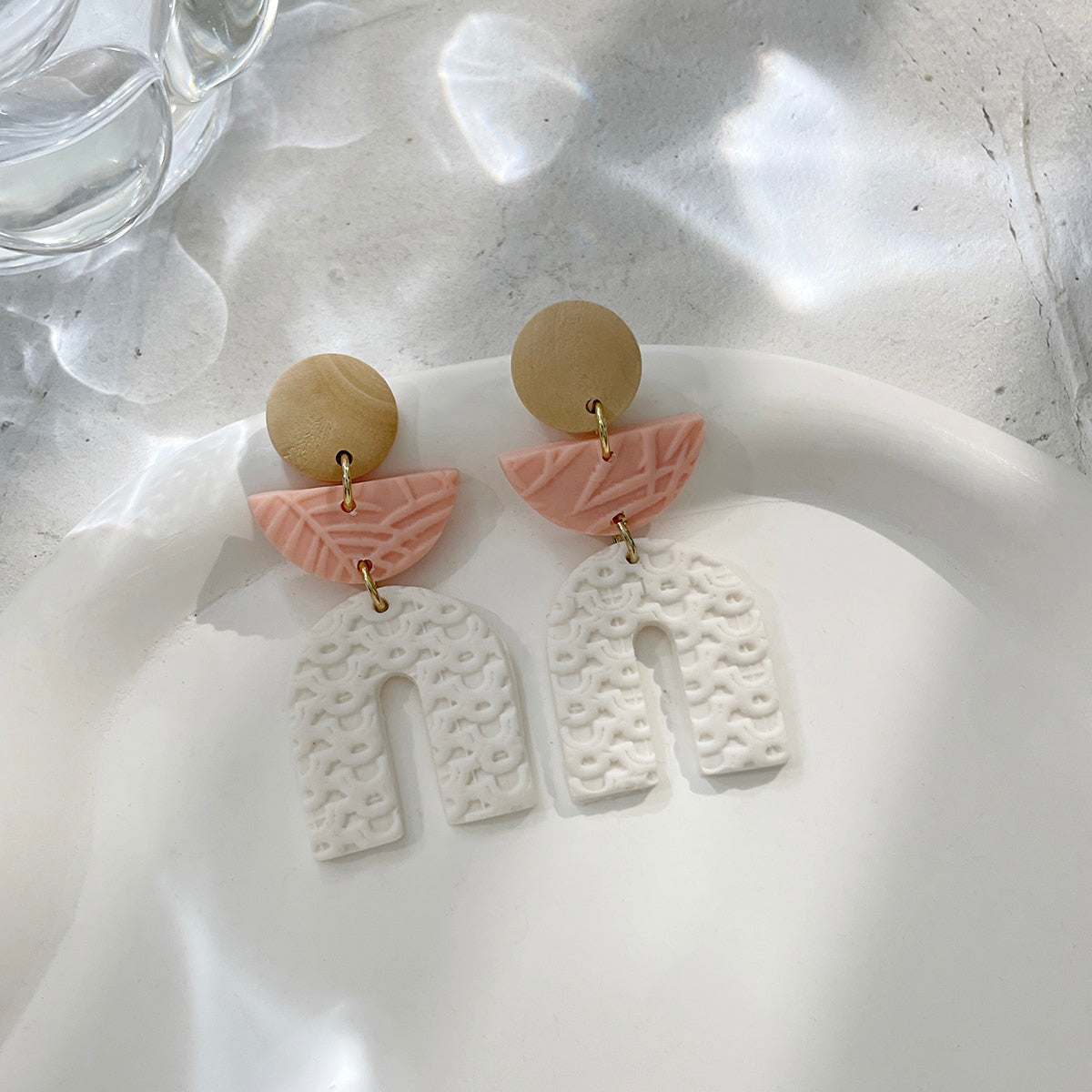 Boucles d'oreilles en argile polymère de Petites Aventures, teintées de blanc et rose poudré, faites à la main avec un motif géométrique