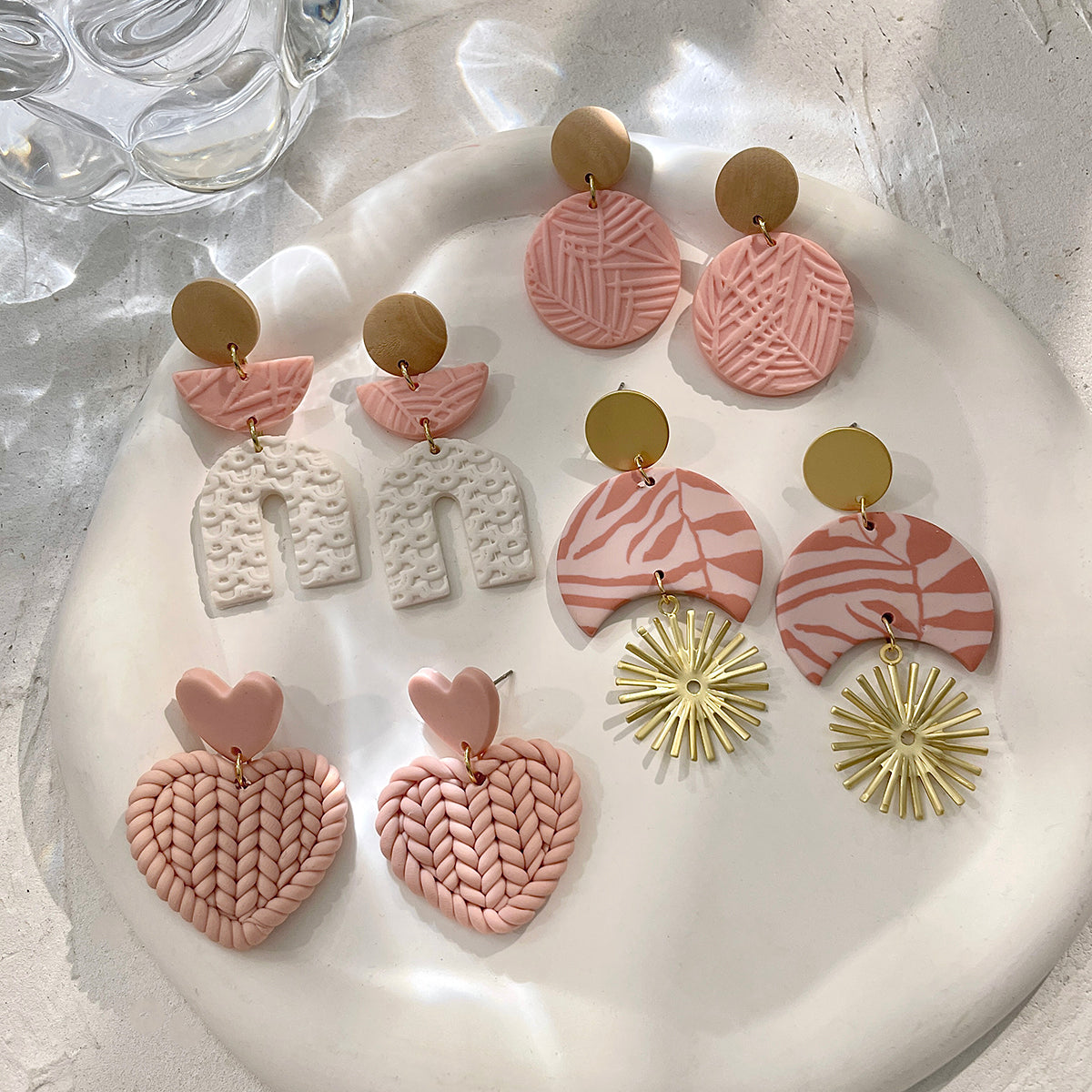 Boucles d'oreilles en argile polymère de Petites Aventures, teintées de blanc et rose poudré, faites à la main avec un motif géométrique